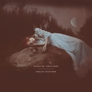Dream Together album cover: it’s a photograph by Natalia Drepina, of a red-haired white woman wearing a Victorian-style white laced gown, she’s peacefully sleeping on a rock. Tall trees and the moon can be seen in the background. The image is in a tone of sepia-maroon color.